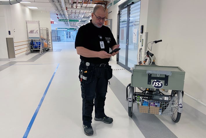 Person från driften skriver på en mobil i korridor vid Danderyds sjukhus.