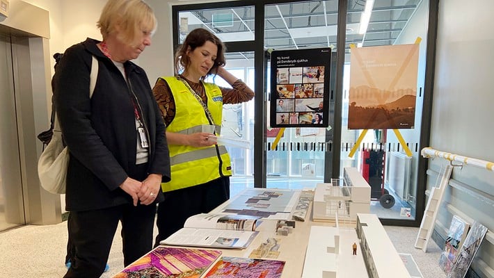 Torunn Skoglund och konstnär Magdalena  Nilsson tittar på konstmaterial under öppet hus vid ny vårdbyggnad.