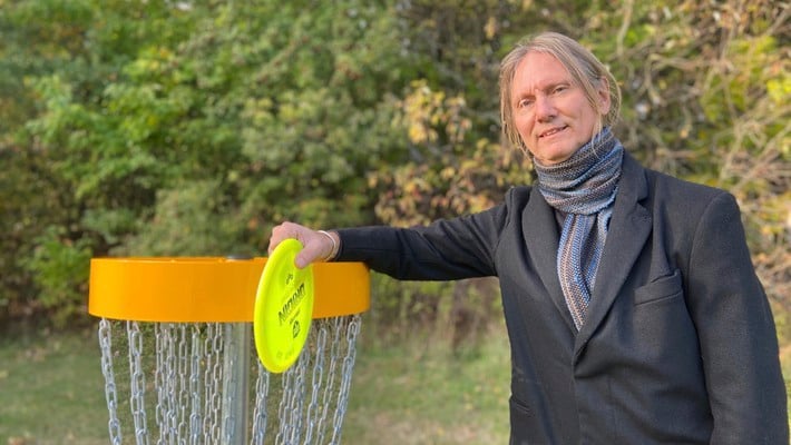 Olof Hillborg vid en korg för discgolf vid Danderyds sjukhus.