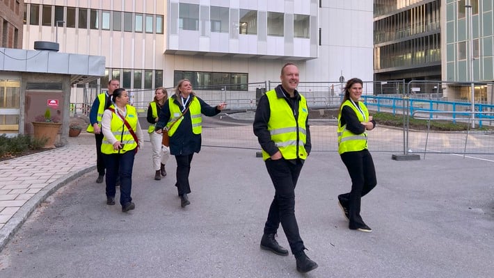 En grupp besökare med varselväst på väg från ny vårdbyggnad vid Danderyds sjukhus.